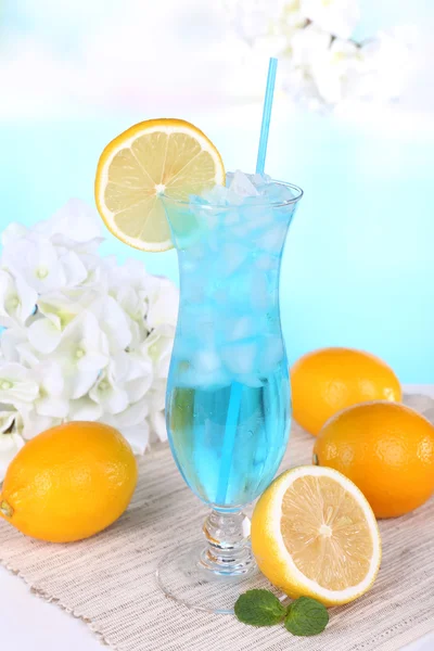 Glass of cocktail on table on light blue background — Stock Photo, Image