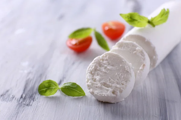 Tasty bushe cheese with basil and tomato, on wooden table — Stock Photo, Image