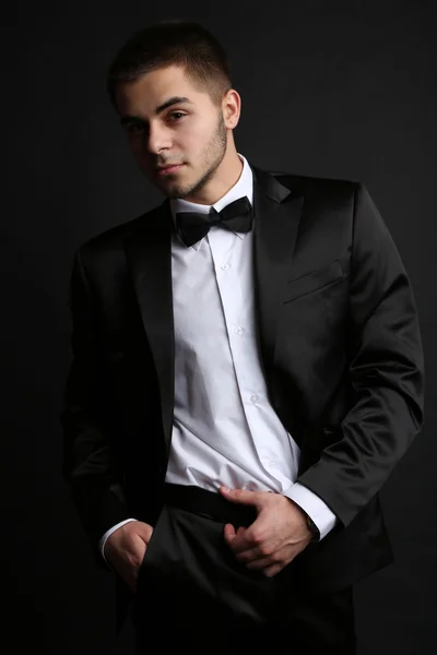 Bello giovane in giacca e cravatta su sfondo scuro — Foto Stock