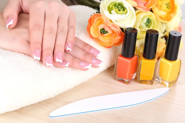 Hermosas manos de mujer con manicura francesa y flores sobre fondo de madera — Foto de Stock