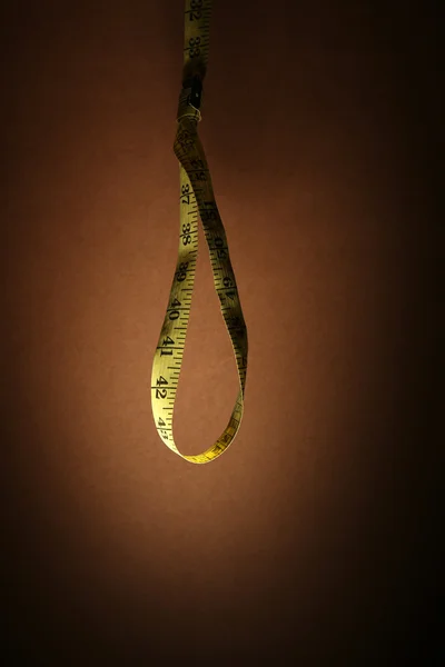 Nastro misura cappio su sfondo marrone - concetto di dieta — Foto Stock