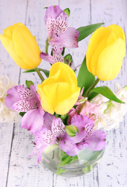 Flowers in vase with candles on wooden background