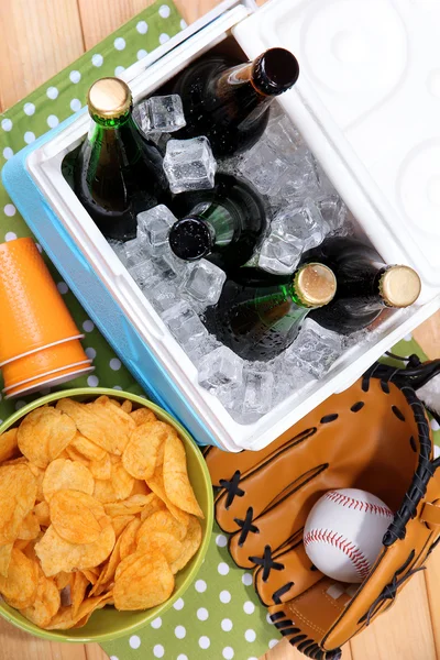 Ice chest full of drinks in bottles on color napkin, on wooden background — Stock Photo, Image