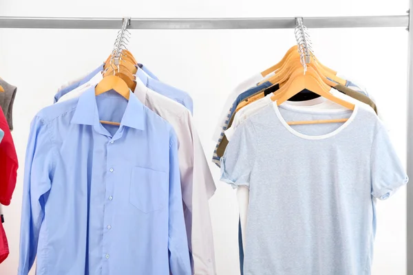 Verschiedene Kleidungsstücke auf Kleiderbügeln, auf grauem Hintergrund — Stockfoto