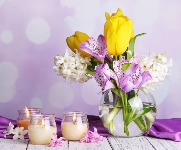 Blommor i vas med ljusen på bordet på ljus bakgrund — Stockfoto