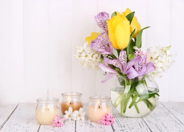 Virágok vázában a gyertyák asztal fából készült háttér — Stock Fotó