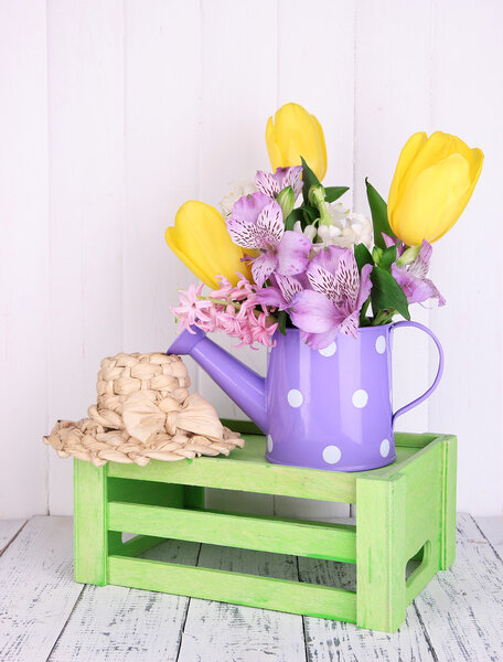 Flowers in watering can on table on wooden background