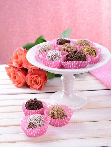 Conjunto de bombones de chocolate sobre mesa sobre fondo rosa — Foto de Stock