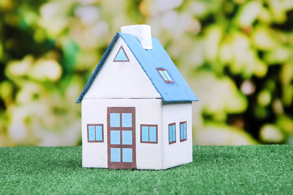 Little house on green grass, on bright background — Stock Photo, Image