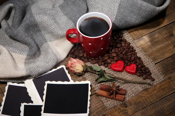 Состав с чашкой кофе, декоративные сердца, клетчатые специи и старые чистые фотографии, на деревянном фоне — стоковое фото