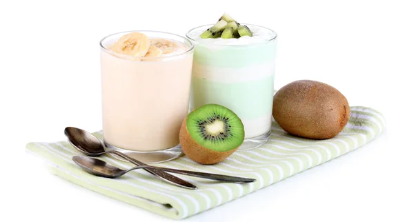 Вкусный йогурт с фруктами вкусы в стаканах на салфетке, изолированные на белом — стоковое фото