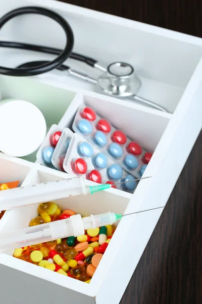 Medical pills,stethoscope,  ampules in wooden box, on color background — Stock Photo, Image