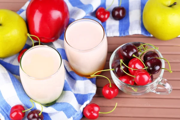 Délicieux yaourt aux fruits goûts dans les verres et fruits frais sur serviette de couleur, sur fond en bois — Photo