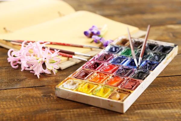 Komposition mit farbenfrohen Aquarellen, Pinseln und Skizzen auf Holzgrund — Stockfoto