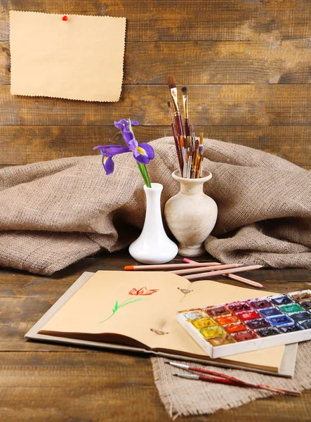 Složení s barevné akvarely, kartáče na vázu a kreslíře na dřevěné pozadí — Stock fotografie
