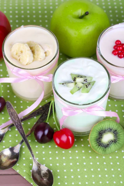Finom joghurt gyümölcs íze, szemüveg és friss gyümölcsök, színes szalvéta háttér — Stock Fotó