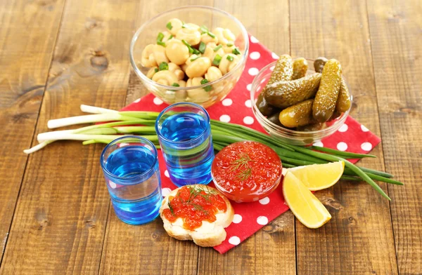 Composition with glass of vodka and marinated mushrooms, cucumbers on wooden background — Stock Photo, Image