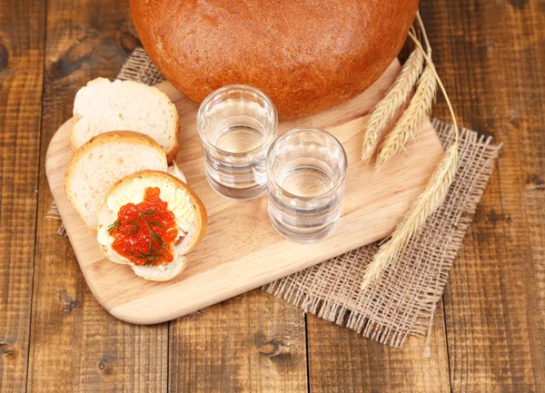 Composição com copos de pão de vodka e caviar vermelho no fundo da mesa de madeira — Fotografia de Stock