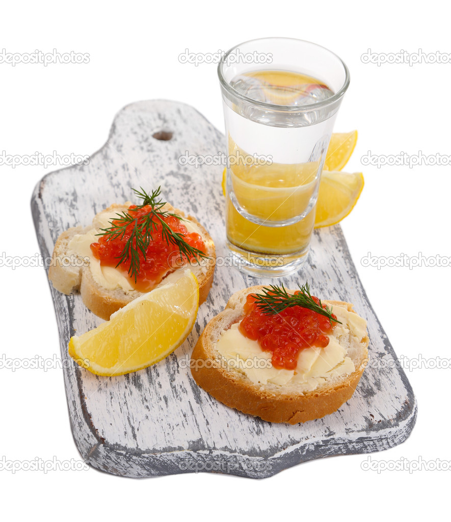 Sandwiches with caviar and vodka on wooden board isolated on white