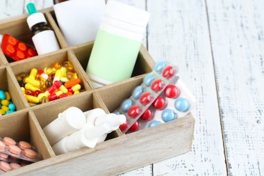 Medical pills, ampules in wooden box, on color background clipart