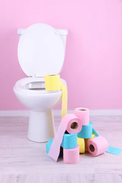 Tigela de vaso sanitário branco e rolos coloridos de papel higiênico, no banheiro — Fotografia de Stock