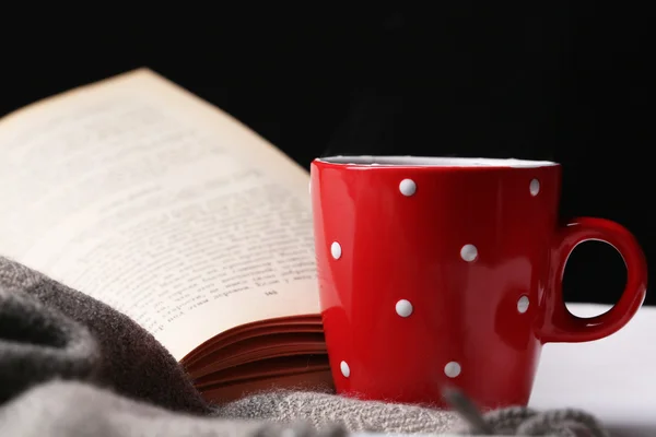 Cup of hot tea with book and plaid on table on dark background — Stock Photo, Image