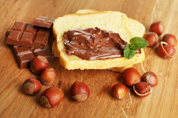 Brot mit süßem Schokoladen-Haselnussaufstrich auf Holzgrund — Stockfoto