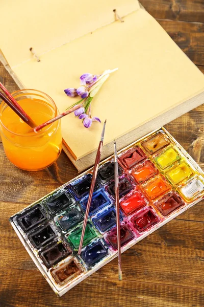 Composition avec aquarelles colorées, pinceaux et esquisse sur fond en bois — Photo