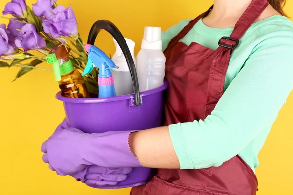 Housewife holding bucket with cleaning equipment on color background. Conceptual photo of spring cleaning. — Stock Photo, Image