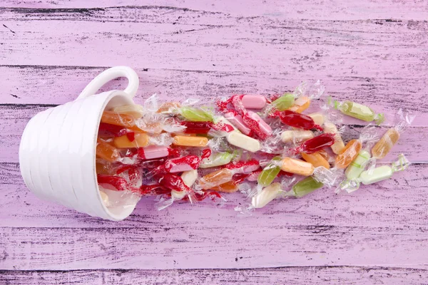 Bonbons savoureux dans une tasse sur fond en bois — Photo