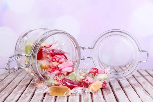 Leckere Bonbons im Glas auf dem Tisch vor hellem Hintergrund — Stockfoto