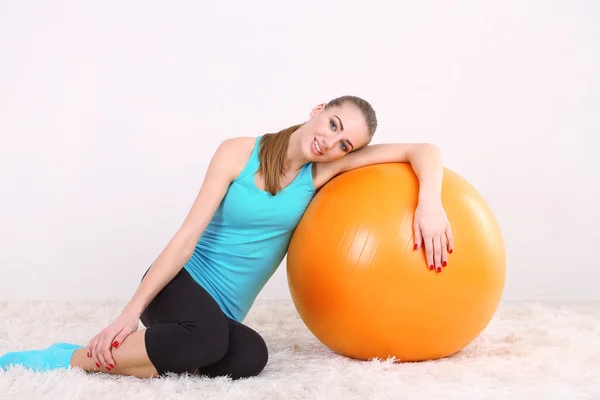 Jovem bela menina fitness exercitando com bola laranja no ginásio — Fotografia de Stock