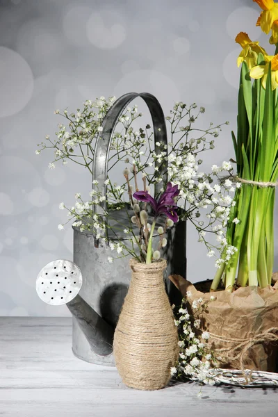 Beautiful spring flowers on old wooden table, on grey background — Stock Photo, Image