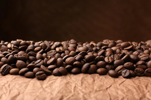 Chicchi di caffè sul tavolo su sfondo marrone — Foto Stock