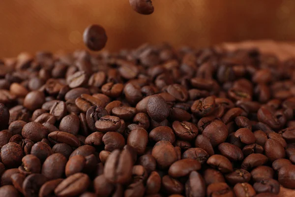 Granos de café sobre mesa sobre fondo marrón —  Fotos de Stock