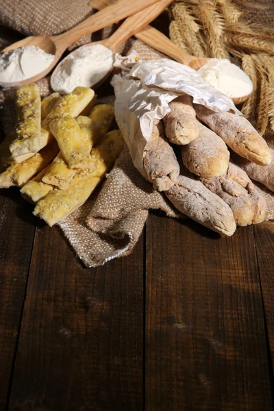 Bread sticks on sackcloth on wooden background — Stock Photo, Image