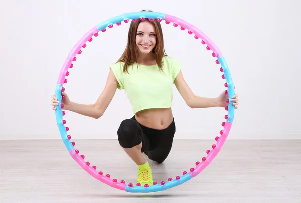 Frau macht Übungen mit Hula-Hoop-Reifen im Zimmer — Stockfoto