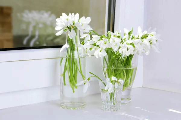 Hermosos ramos de gotas de nieve en jarrones en alféizar de ventana —  Fotos de Stock