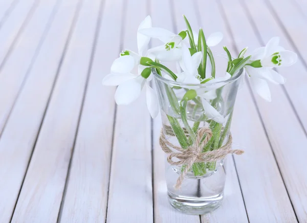 Beautiful bouquets of snowdrops in vases on wooden background — Stock Photo, Image