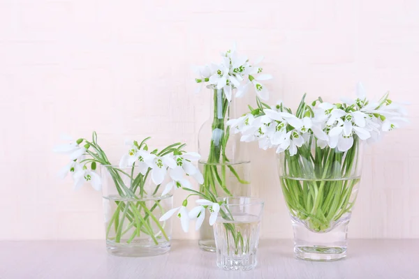 Beautiful bouquets of snowdrops in vases on light background — Stock Photo, Image