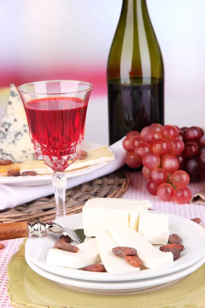 Prato de queijo sortido, uva e copo de vinho na mesa, no fundo claro — Fotografia de Stock