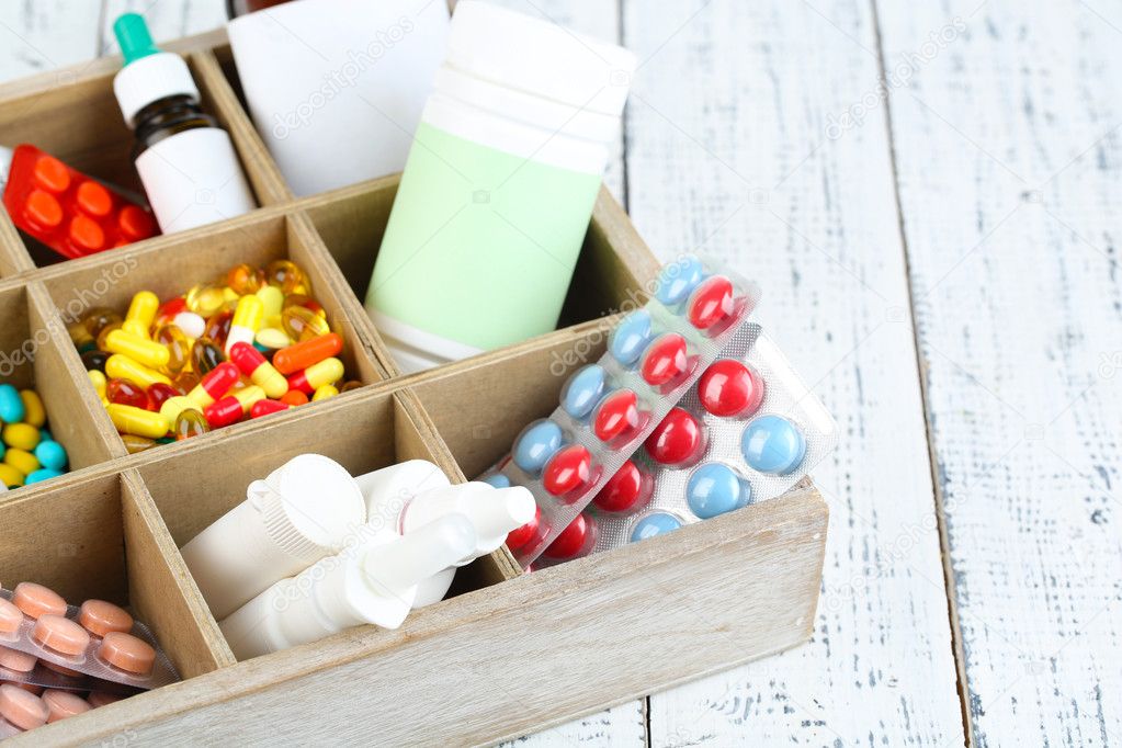 Medical pills, ampules in wooden box, on color background