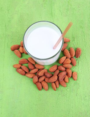 badem sütü kabı içinde kase renkli ahşap zemin üzerinde bademli