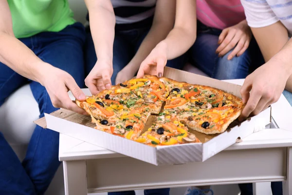 Grupo de jóvenes amigos comiendo pizza en el salón en el sofá — Foto de Stock