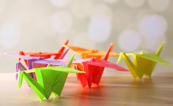 Origami-Kraniche auf Holztisch, auf hellem Hintergrund — Stockfoto