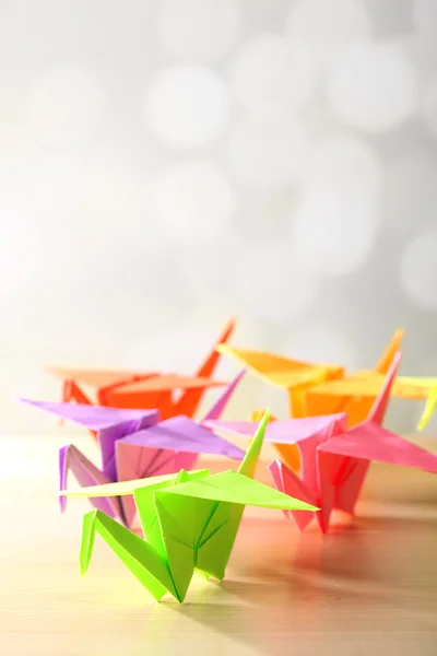 Origami kranen op houten tafel, op lichte achtergrond — Stockfoto