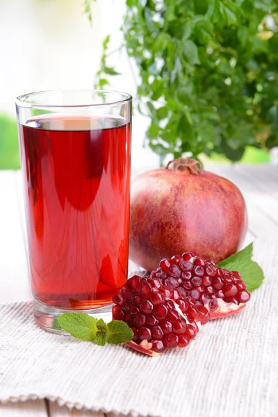 Melograni maturi con succo sul tavolo su sfondo chiaro — Foto Stock