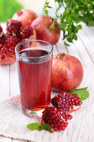 Ripe pomegranates with juice on table on light background — Stock Photo, Image