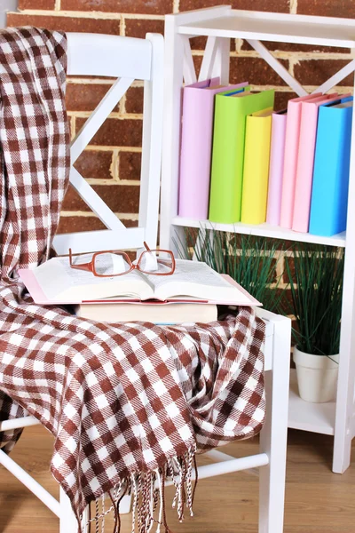 Composición con gafas y libros, sobre silla, sobre armario y fondo de pared — Foto de Stock