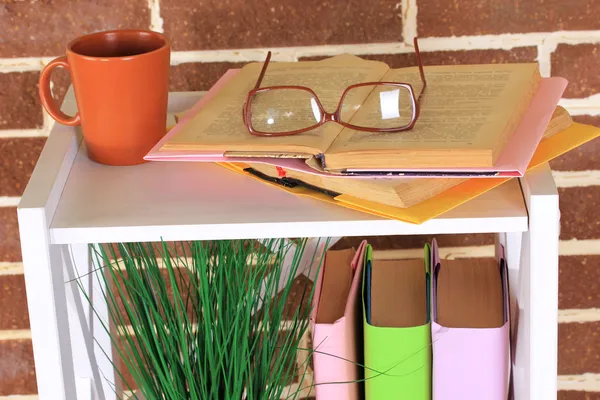 Composition with glasses and books, on cabinet, on color wall background — Stock Photo, Image